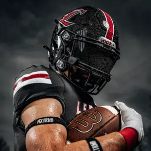 A football player couches a football in his bicep