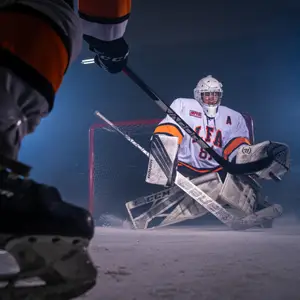 A hockey goalie stares down an opponent's hockey stick