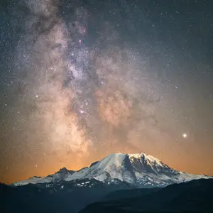 A shot of the milky way in the night sky set behind a towering mountain