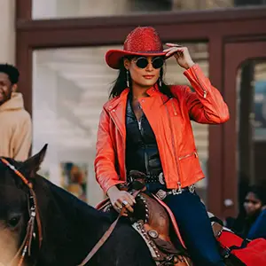 Cowgirl in a red hat and coat riding a black horse