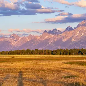 Landscape with mountains, pink and blue skies, and a grassy field
