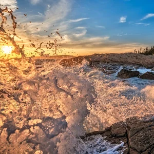 a wave splashes on a sunset beach