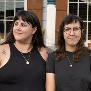 a couple poses in front of a brown building