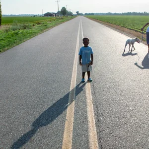 a child stands in the middle of an empty road