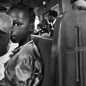 a child sits in a church pew, her face is partially obscured