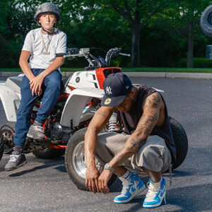 posing with an atv on an asphalt parking lot