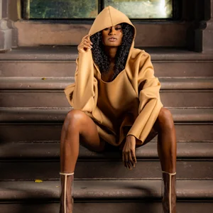 woman in a golden hoodie sits on steps