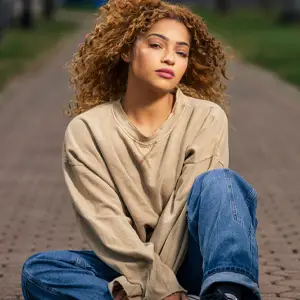 Young woman in casual clothes, sitting on a brown stoned path