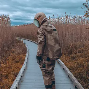 Deep sea diver walking along a path surrounded by tall reeds