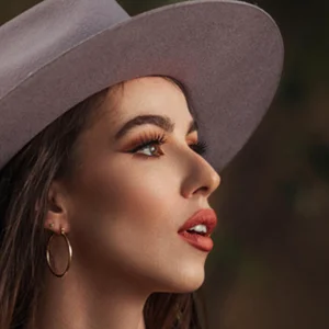 model in a mauve colored hat with red lipstick and hoop earrings