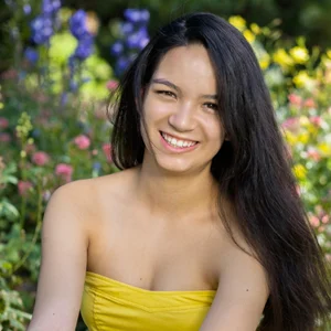 a dark haired woman in a yellow dress smiling