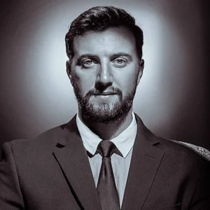 man in a dark suit with slicked back hair