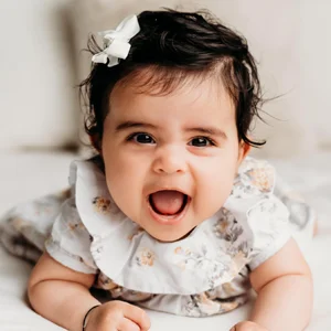a happy baby wearing a bow in her hair