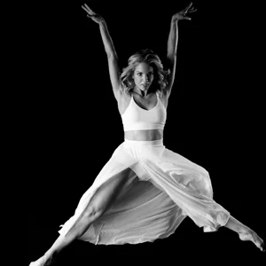 black and white photo of a dancer in a white dress leaping