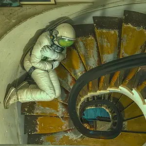 An astronaut lays huddled on a spiral staircase