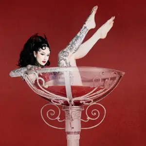 Woman sits in a giant wine glass with her legs in the air