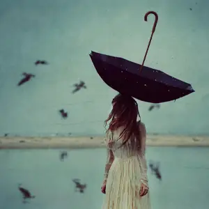 Woman in white, standing in a lake, with an upturned umbrella on top of her head