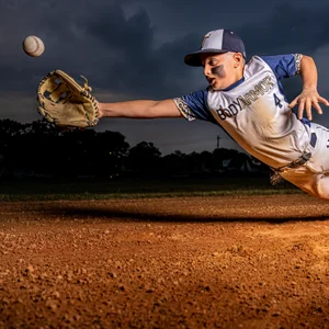 a kid baseball player dives to catch a ball