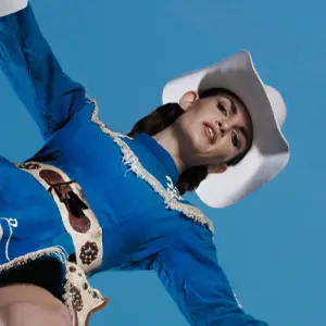 Cowgirl in blue outfit and white hat looking down
