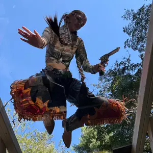 Woman in cowgirl outfit kneeling on plexiglass