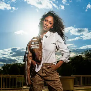 Model with brown jacket posed against a bright blue sky