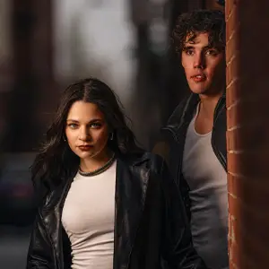 Man and woman in an alley, posing near a brick building