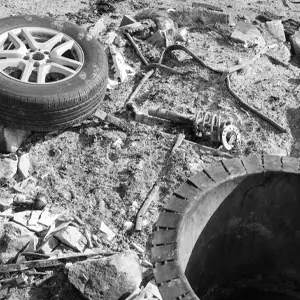 Black and white photo of an old tire and random debris on the ground