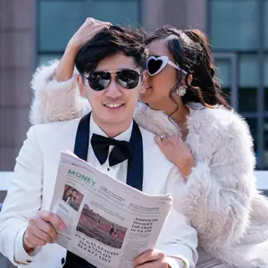 Bride and groom posing playfully with sunglasses and a newspaper