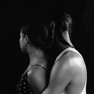 Man embracing a woman from behind, with their faces turned away