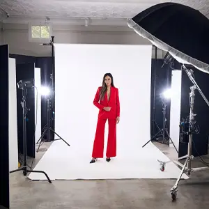 Model in red suit standing in a studio lighting setup
